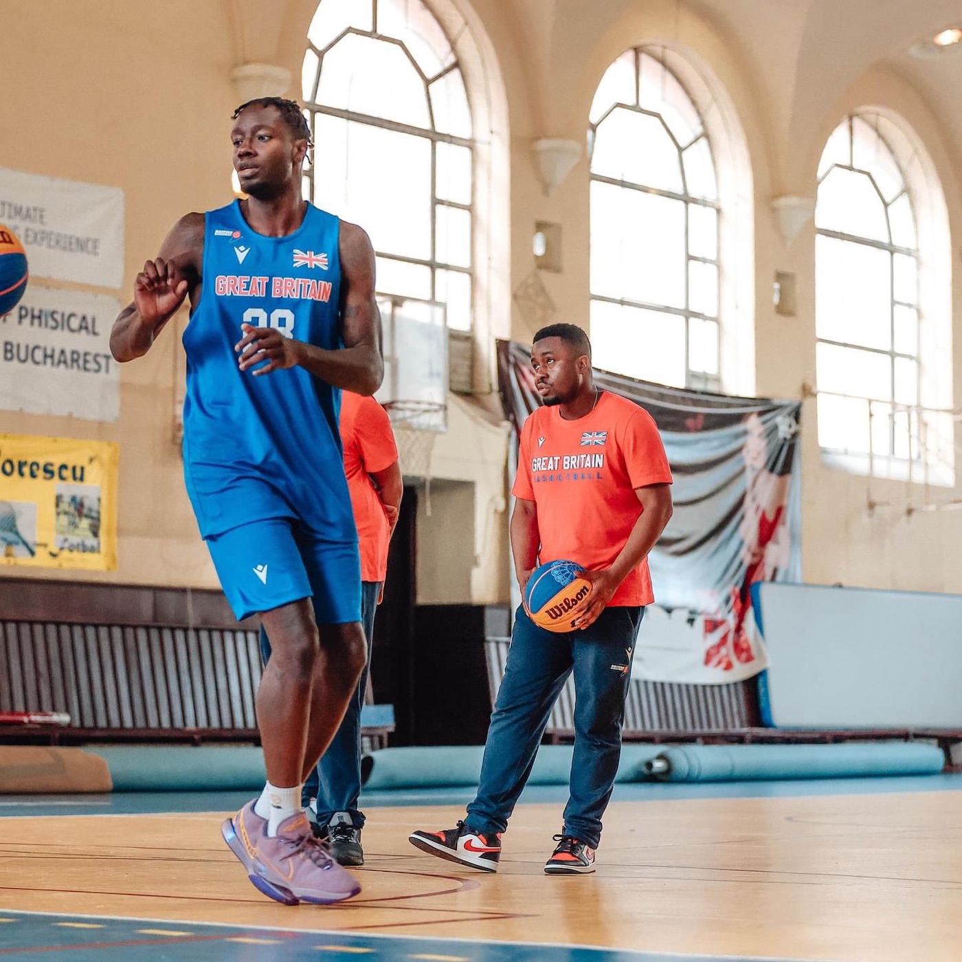 Coach running a session with a Great Britain player in an arched-window gym
