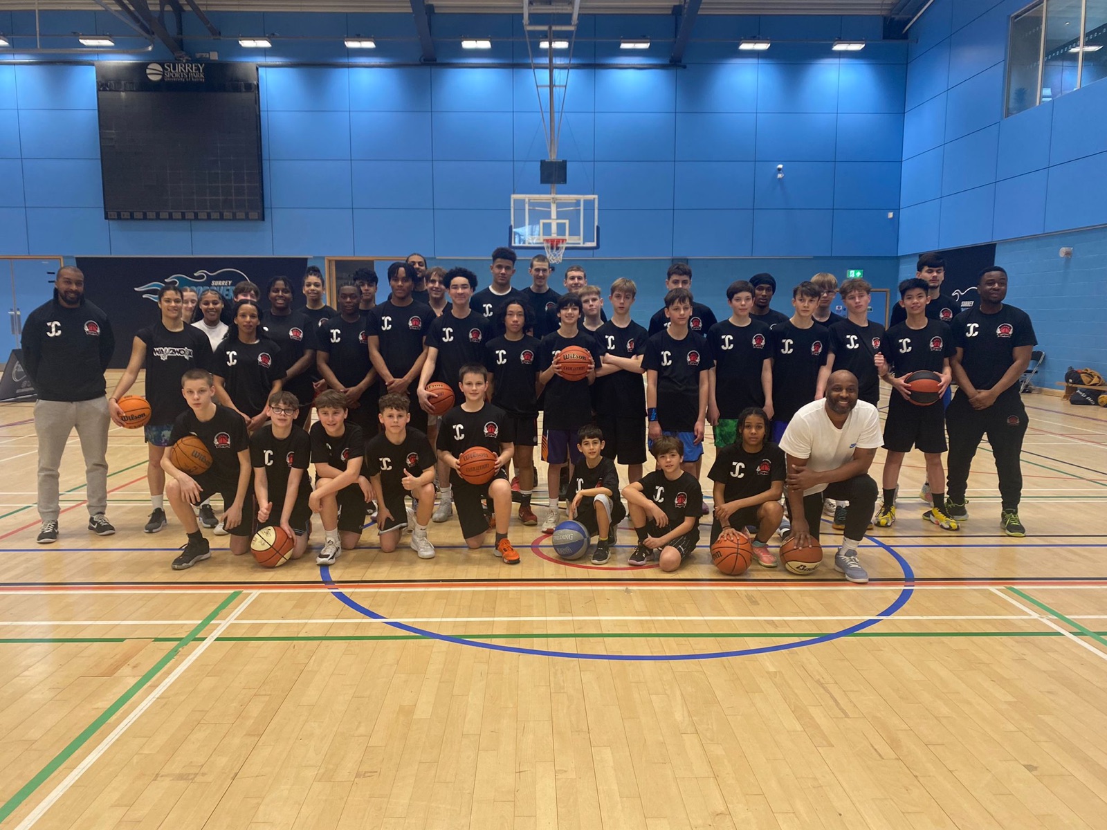 Way2Work academy players and coaches lined up on court with basketballs